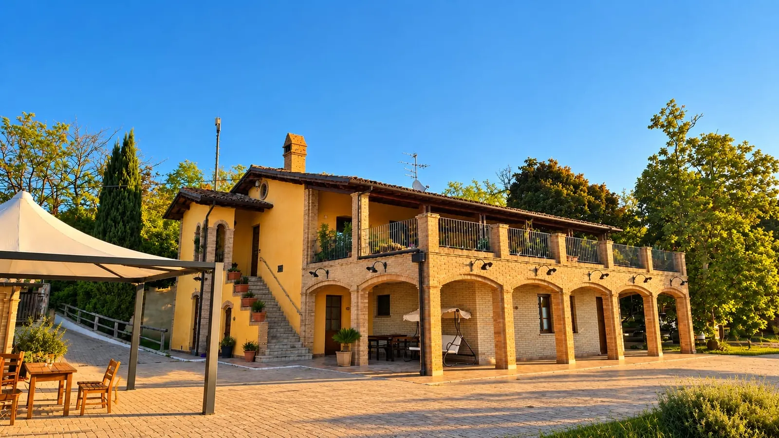 La casa con il loggiato ad archi in mattoni e la terrazza, vista dal piazzale con il gazebo