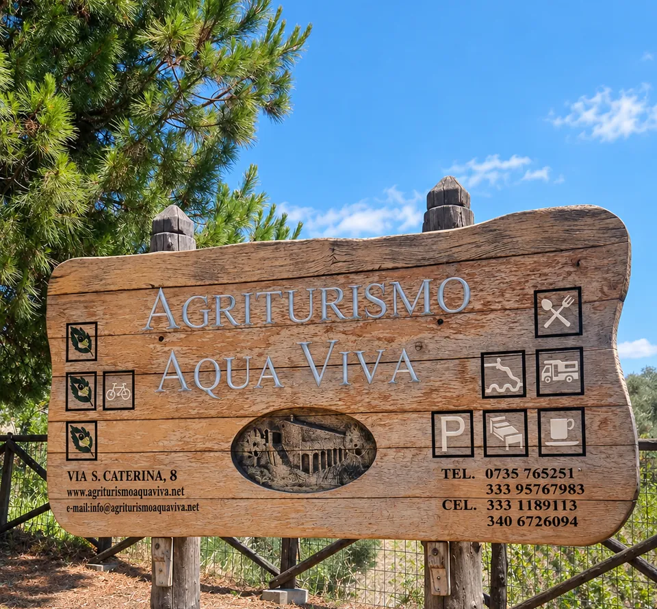 Il cartello di legno all'ingresso: Agriturismo Aqua Viva, tra i pini