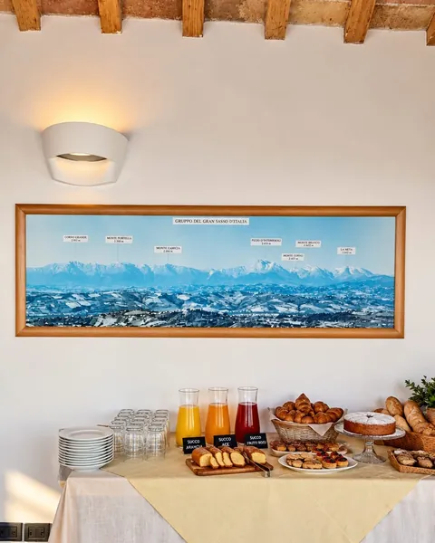 Il buffet della colazione nella sala, con succhi, cornetti e dolci sotto un grande pannello delle montagne