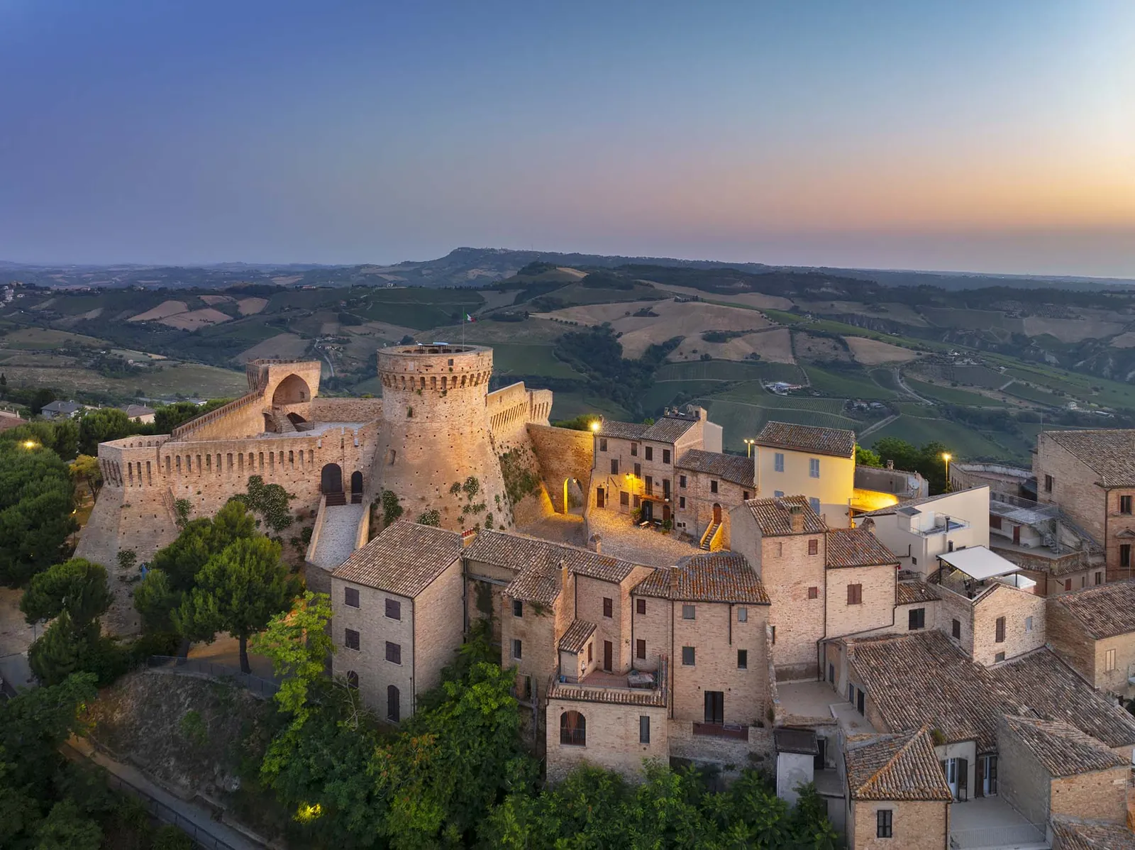 La Rocca di Acquaviva Picena e le case del borgo all'imbrunire, con le colline dietro
